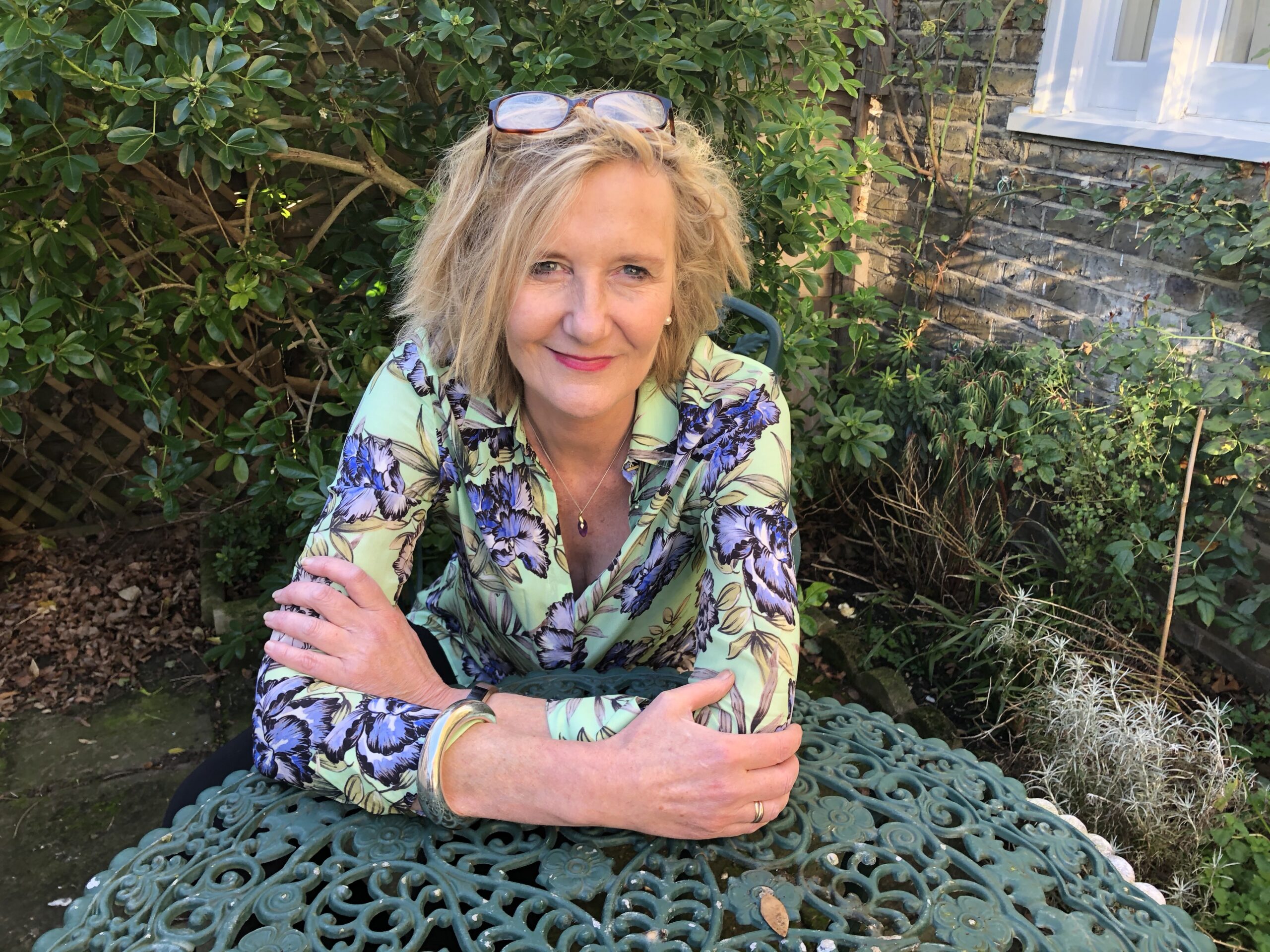 Catherine Bailey sets outside leaning her arms on a table.