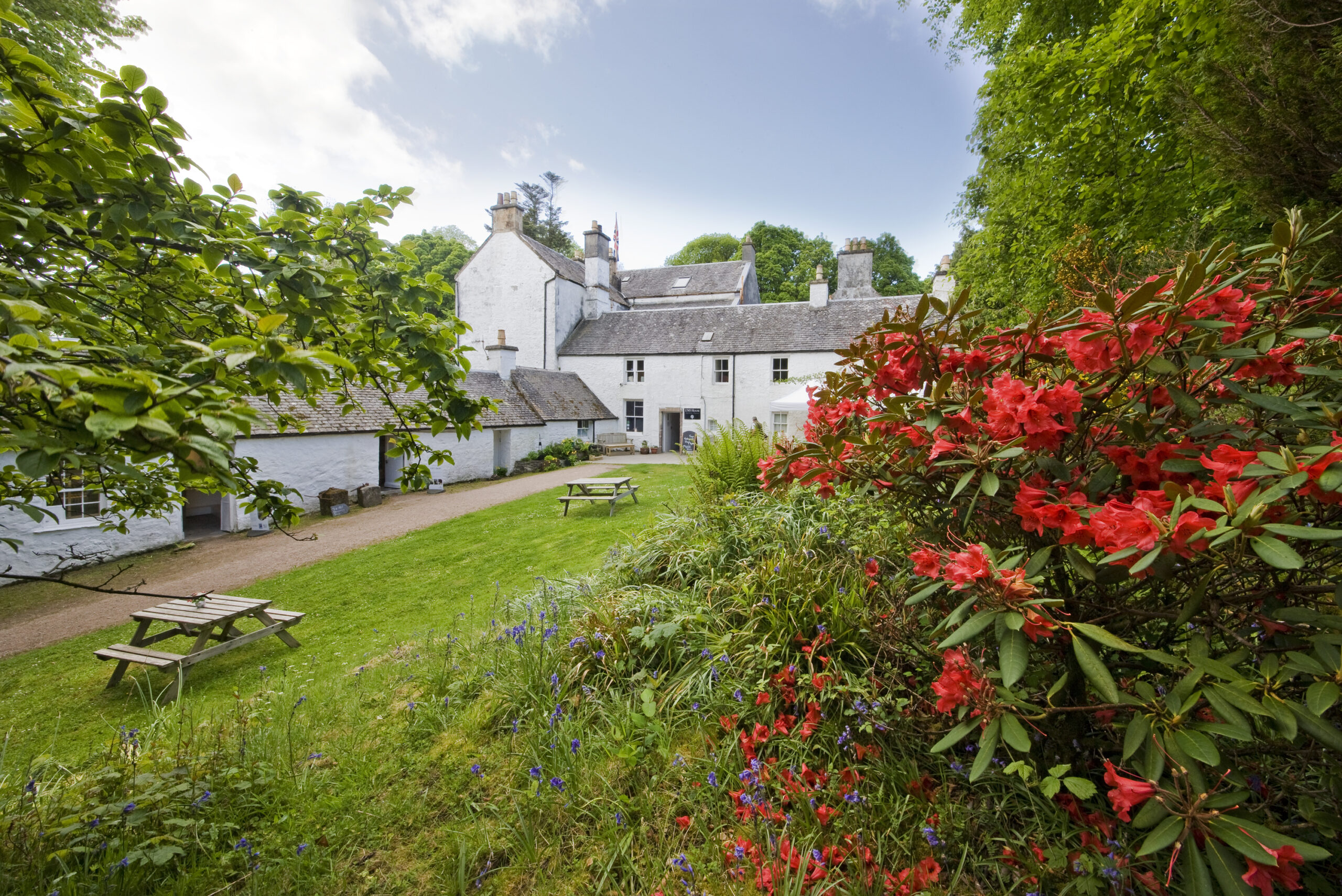 Exterior of Dunollie museum with flowers and grass in the foreground.