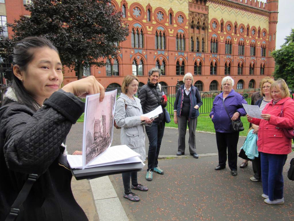 A tour guide holds up a historic drawing for a group of visitors