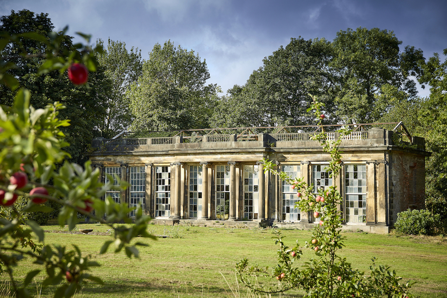 Exterior of the Grade II* Listed Camellia House at Wentworth Woodhouse with lawns in the foreground and trees to the rear.
